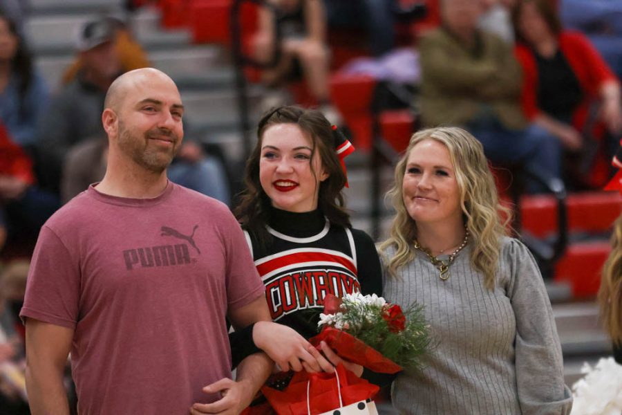 Senior cheerleader Brielle Fawson stands with her parents during Sr night