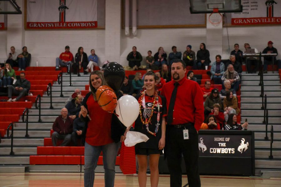 Morgan Thornton standing with her parents during girls basketball Senior night 