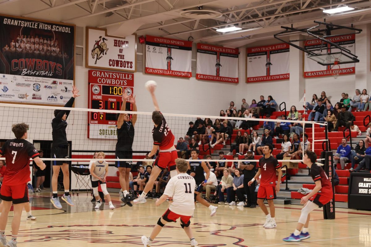 #23 Corbin Hislop spikeing the ball for a point over the Stansbury blockers 