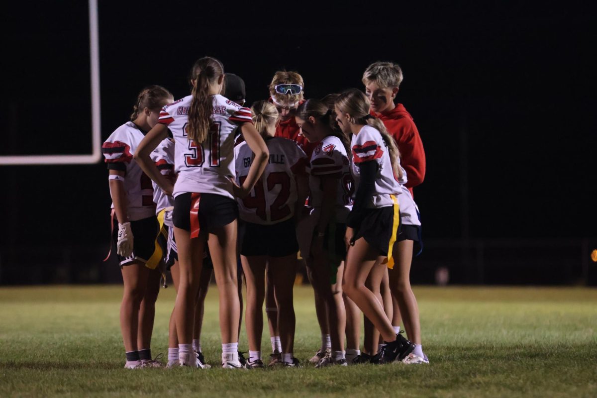 Freshmen huddled at the powder puff game game planning against the seniors 